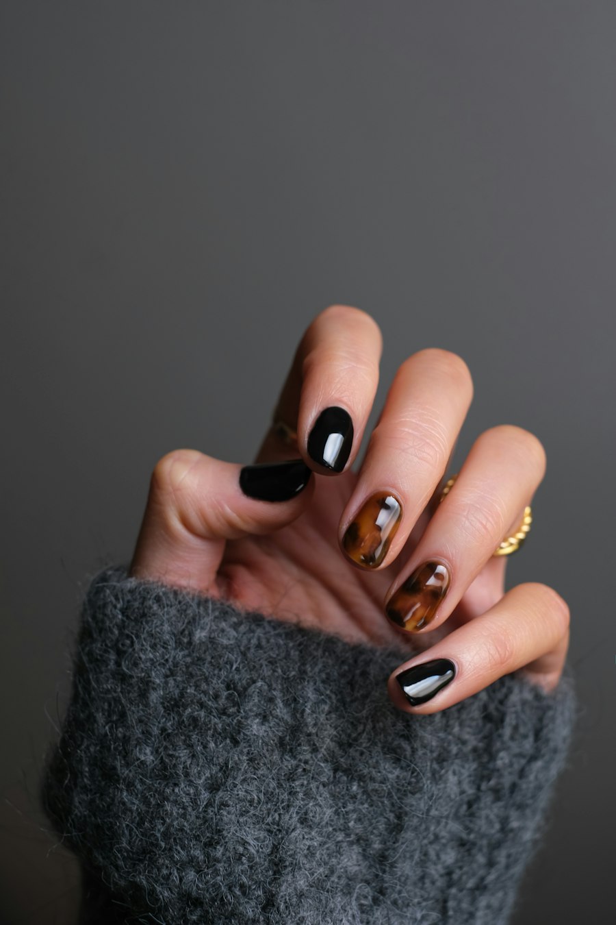 Foto ilustrativa: Unhas esmaltadas em tons escuros